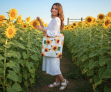 Woman holding a tote bag with sunflower design in a sunflower field