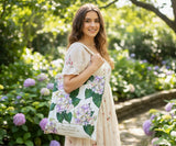 Woman holding a hydrangea floral tote bag in a garden setting