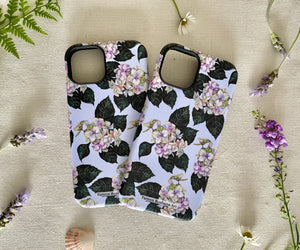 Two iPhones in floral cases side by side, showcasing the artistic hydrangea design.