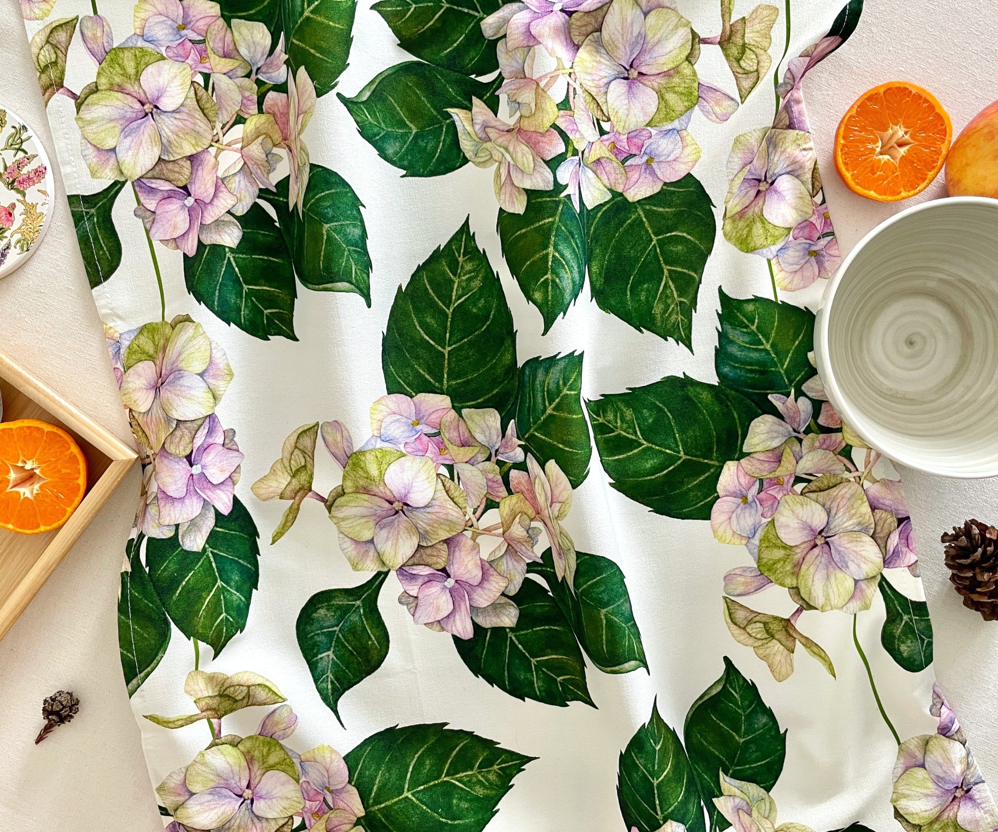 Front view of Hues of Serenity Hydrangea tea towel on table with soft floral design.