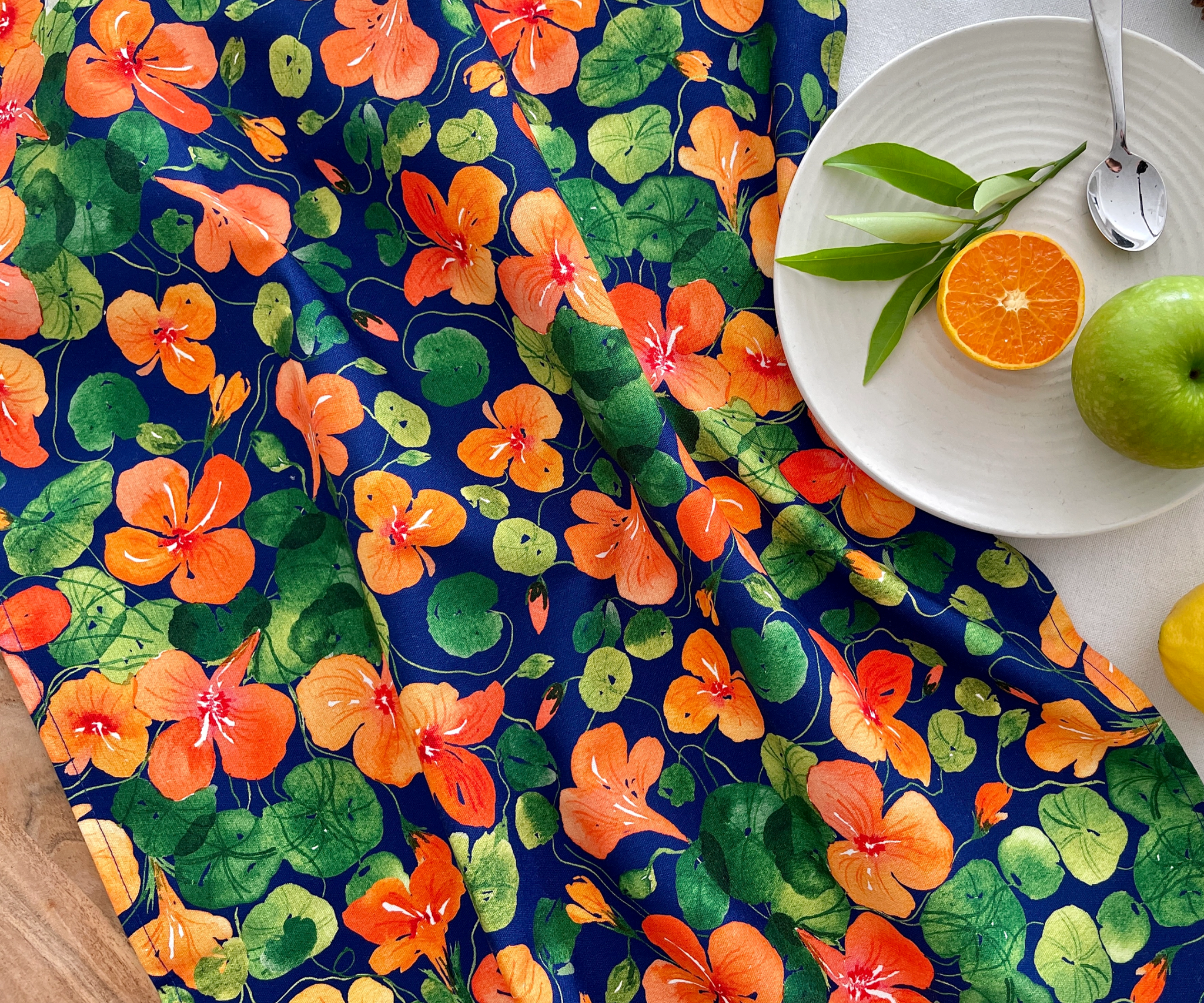 Front view of Nasturtium Dreams tea towel on a table, featuring bold watercolour nasturtiums.